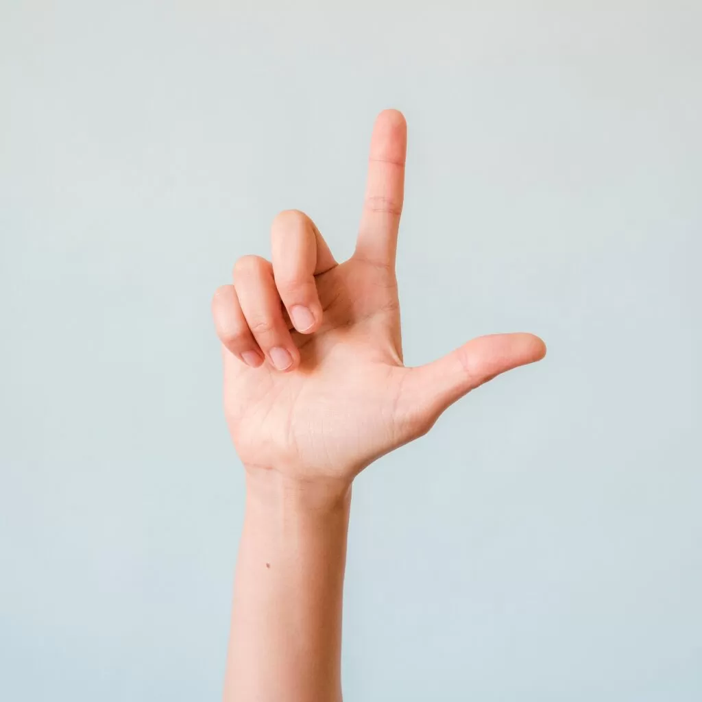 Hand with index finger pointing upward against a pale blue background.