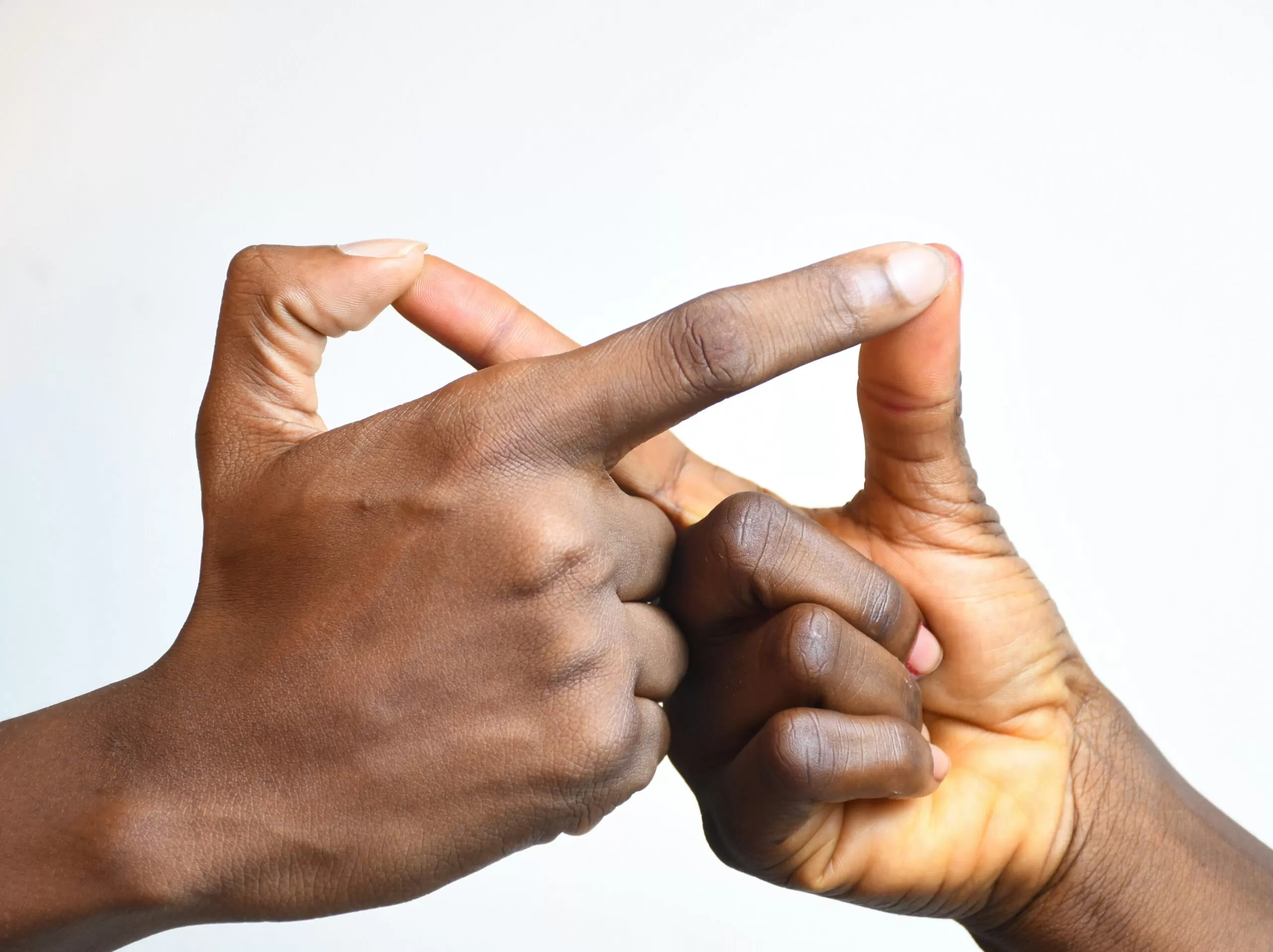 Close-up of two hands interlaced fingers forming a connection against a light background.